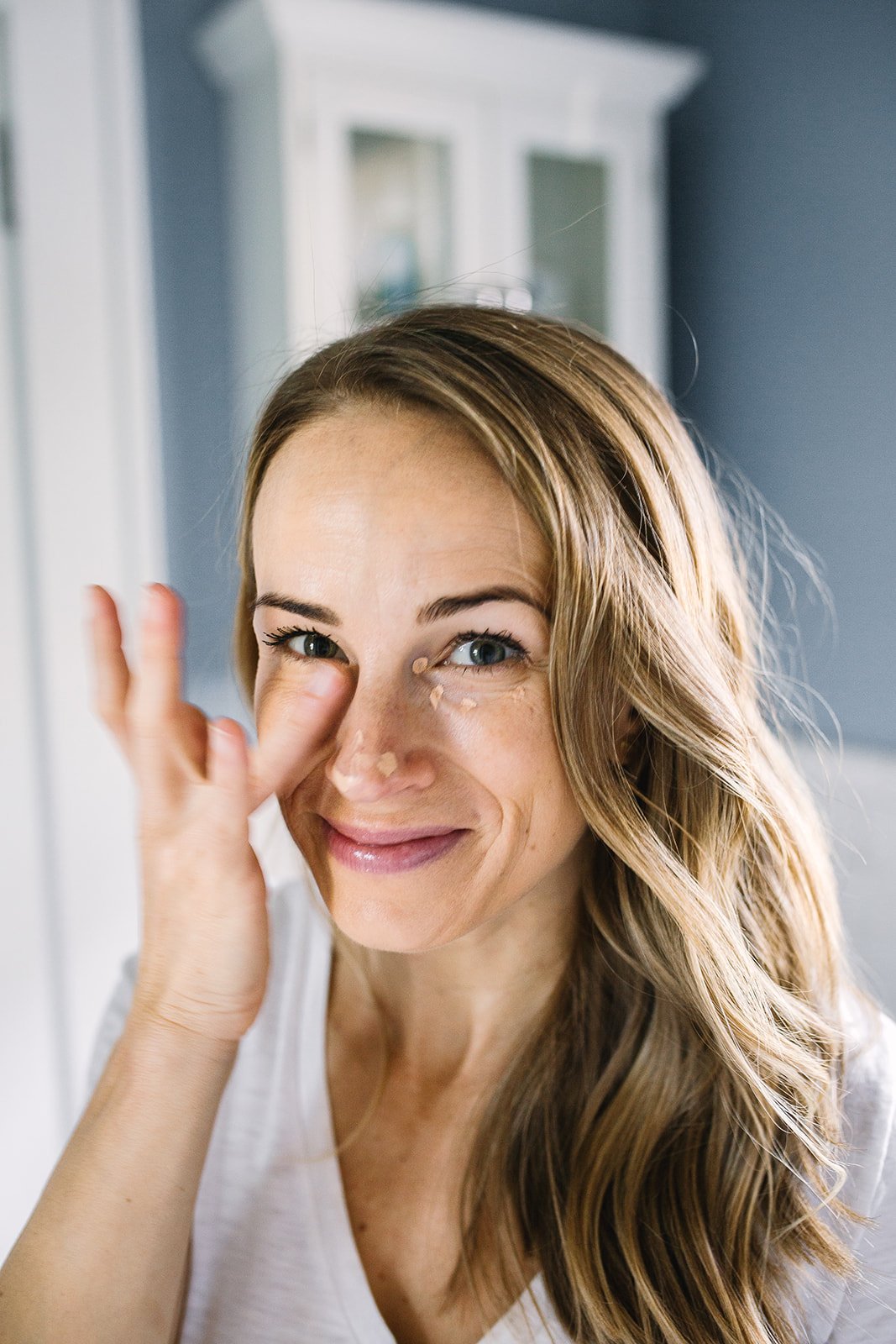 woman applying concealer on face