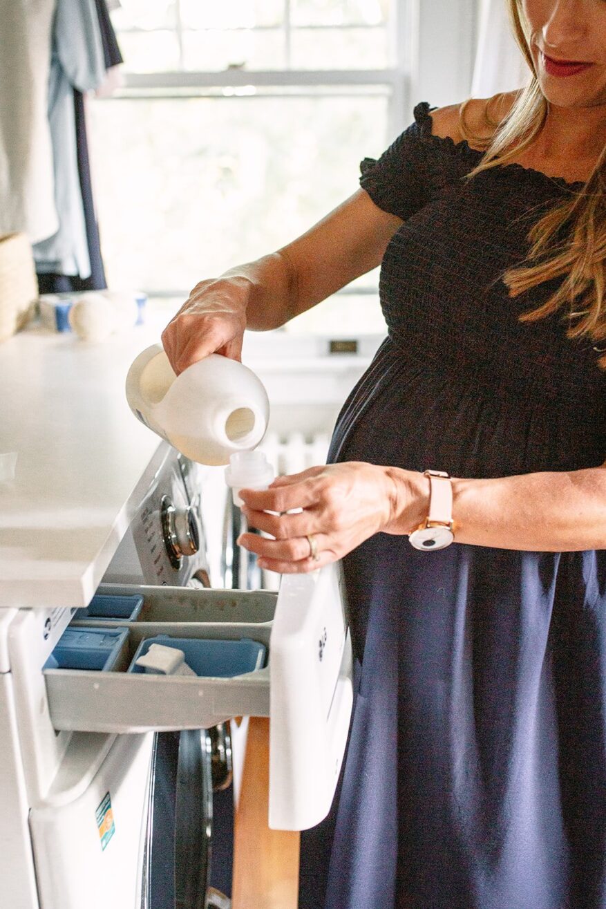 Woman measuring Branch Basics Oxygen Boost for laundry