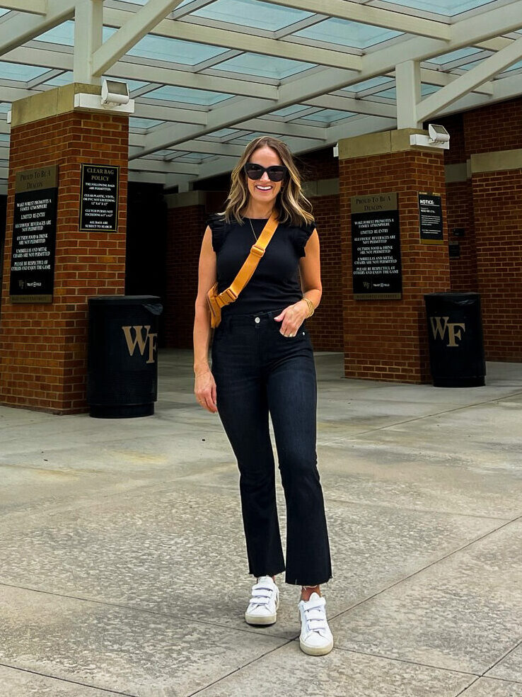 Woman wearing black top and black jeans one of the outfits for what to wear to a football game