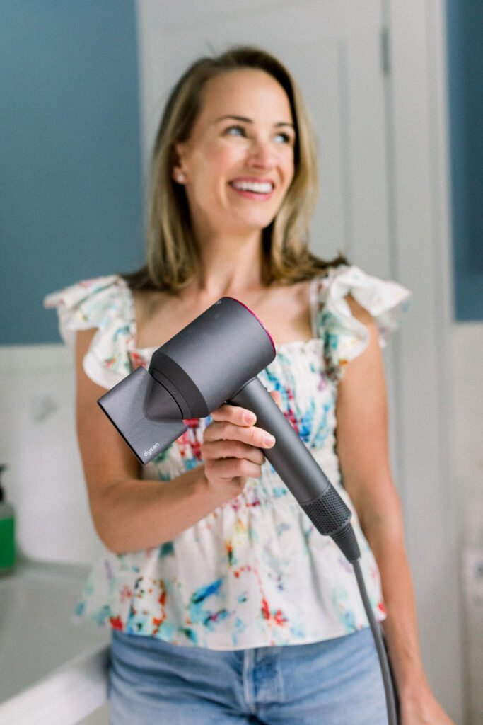 Woman holding Dyson Hair Dryer with attachment