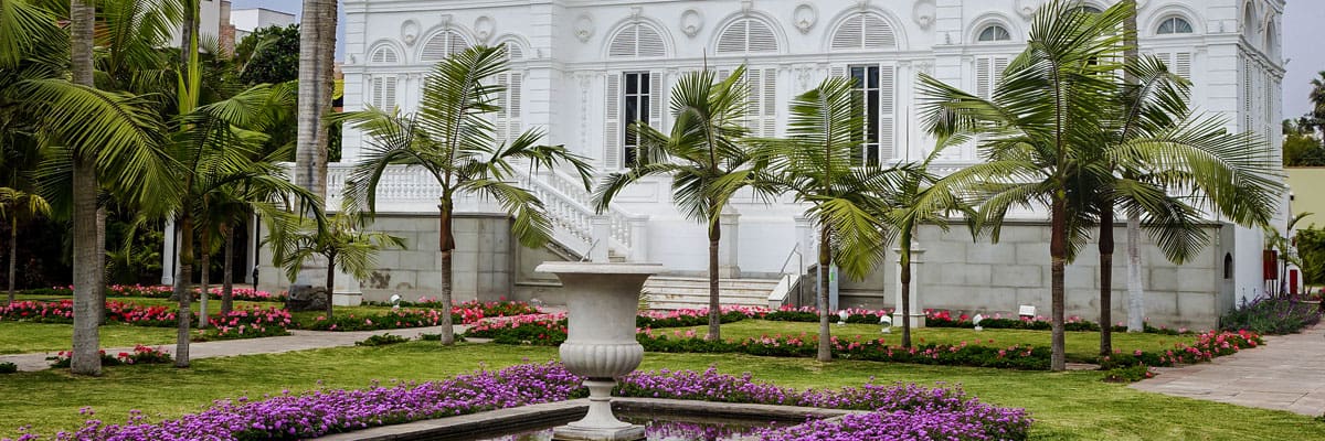 Palm trees around white colonial building of Museo Pedro de Osma in Lima, Peru